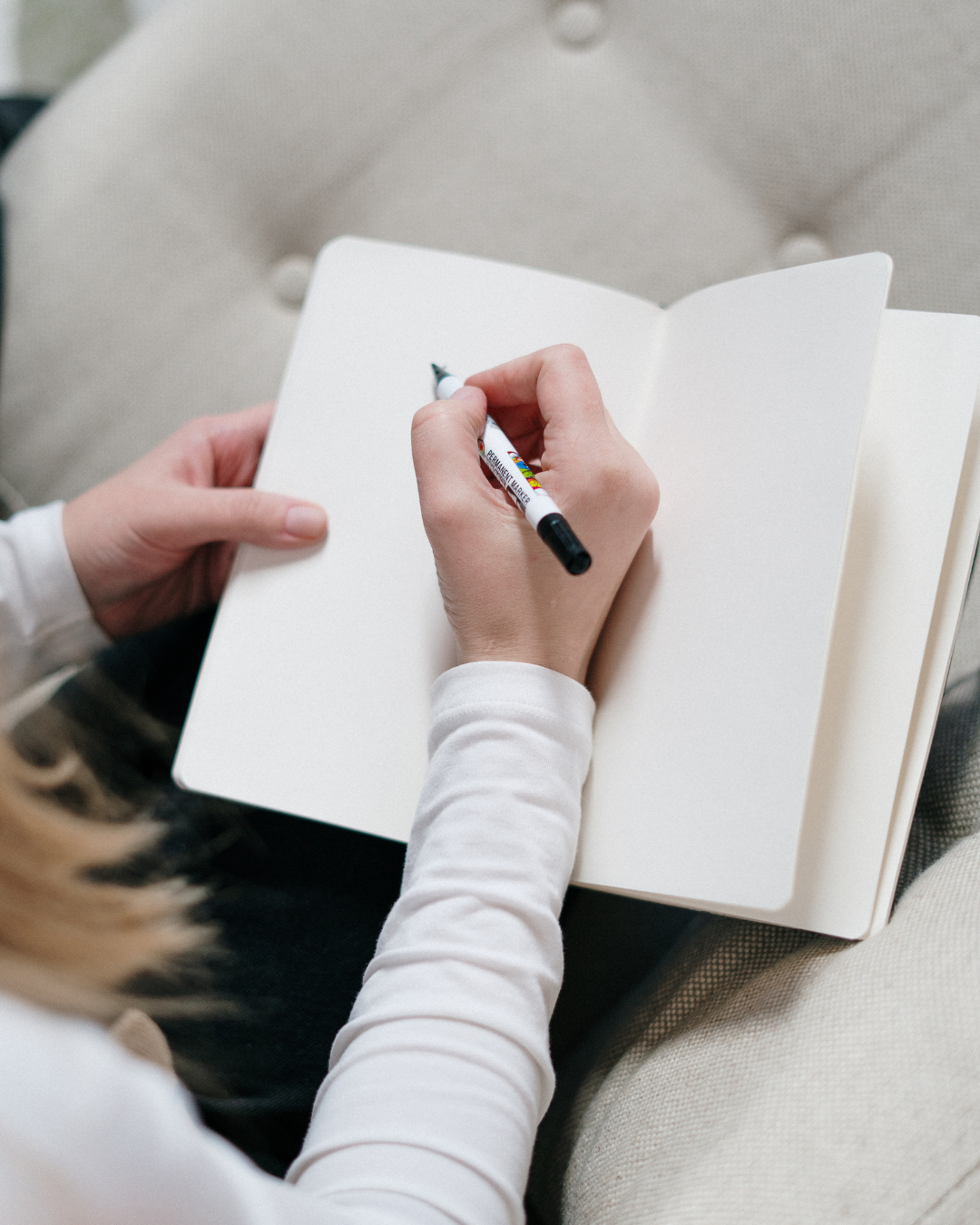 Beruf und Bildung Frau, die mit einem Notizbuch und einem Kugelschreiber in der Hand auf einem Sofa sitzt