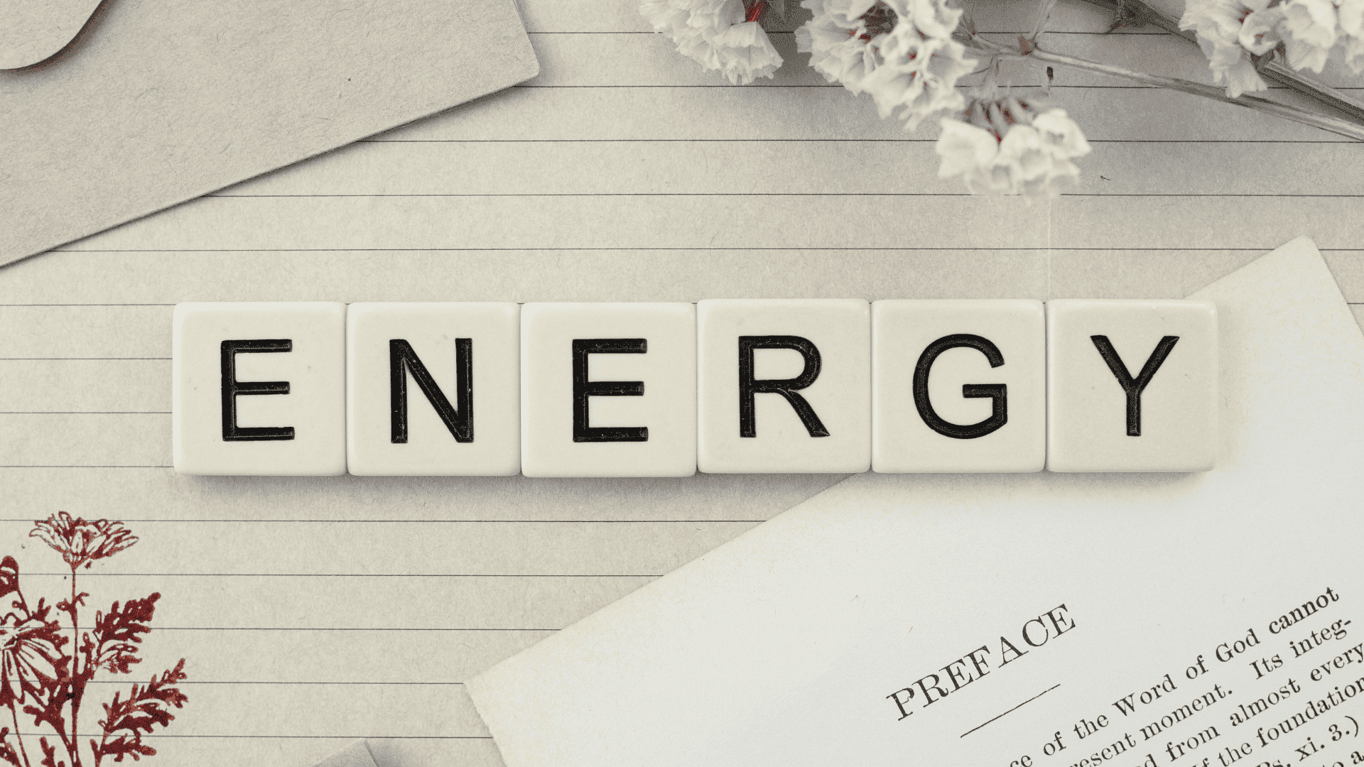 Mehr Lebensenergie bekommen Mehr Lebensenergie bekommen: Auf einer beigen Unterlage liegen Steine mit jeweils einem Buchstabe, was im Ganzen Energy ergibt. Vorne rechts befindet sich ein Blatt Papier mit einem englischen Text. Über dem Wort Energy sind weiße Blumen und ein zugeklappter Laptop.