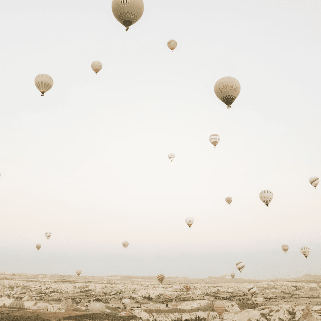 Eine Fülle an Ballons, die alle in der Luft über einer Stadt schweben.