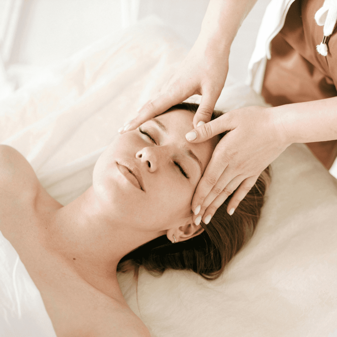 Muskelverspannungen lösen: Das Bild zeigt eine Frau auf einer Liege, die von zwei Händen im Gesicht berührt wird.